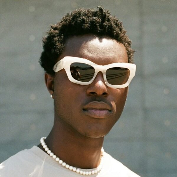 a man wearing sunglasses and a pearl necklace